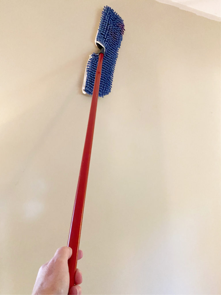 Dusting the walls with long red handled mop to get ready for master bedroom refresh