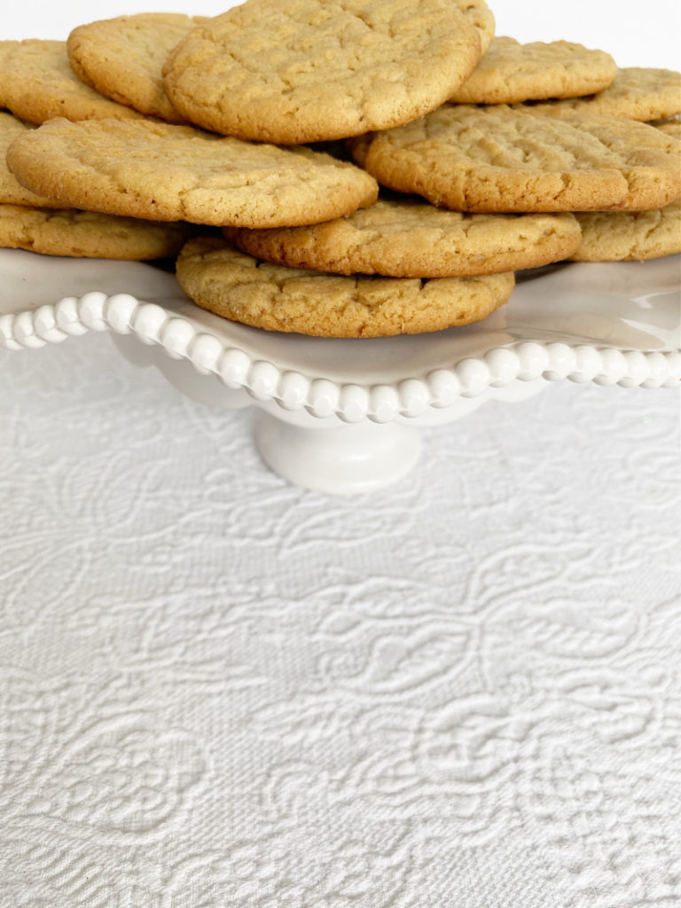 Fresh baked peanut butter cookies on ruffled plate on white table cloth