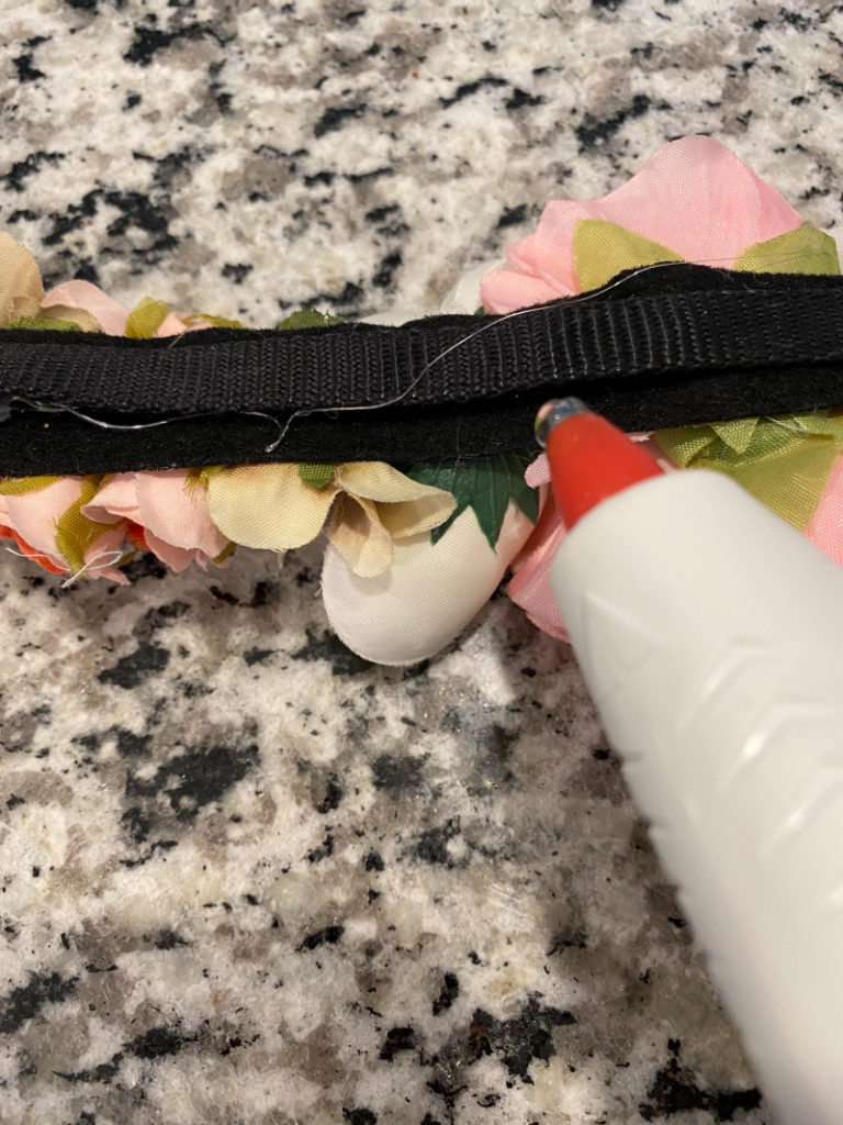 glue gun adding more glue to bland spot between two bands of dog collar and floral strip