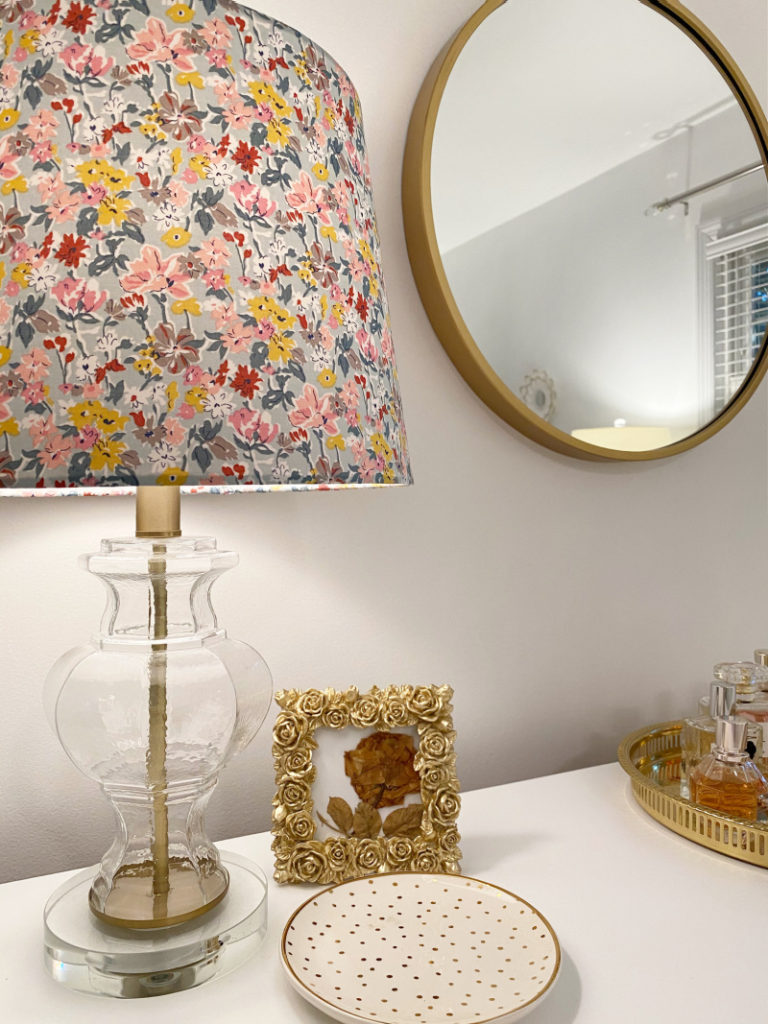 Colorful floral lamp and round gold mirror in glamorous master bedroom makeover