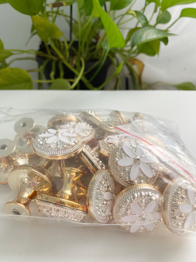 Clear bag of shiny white daisy flower drawer knobs for the elegant guest room makeover one room challenge