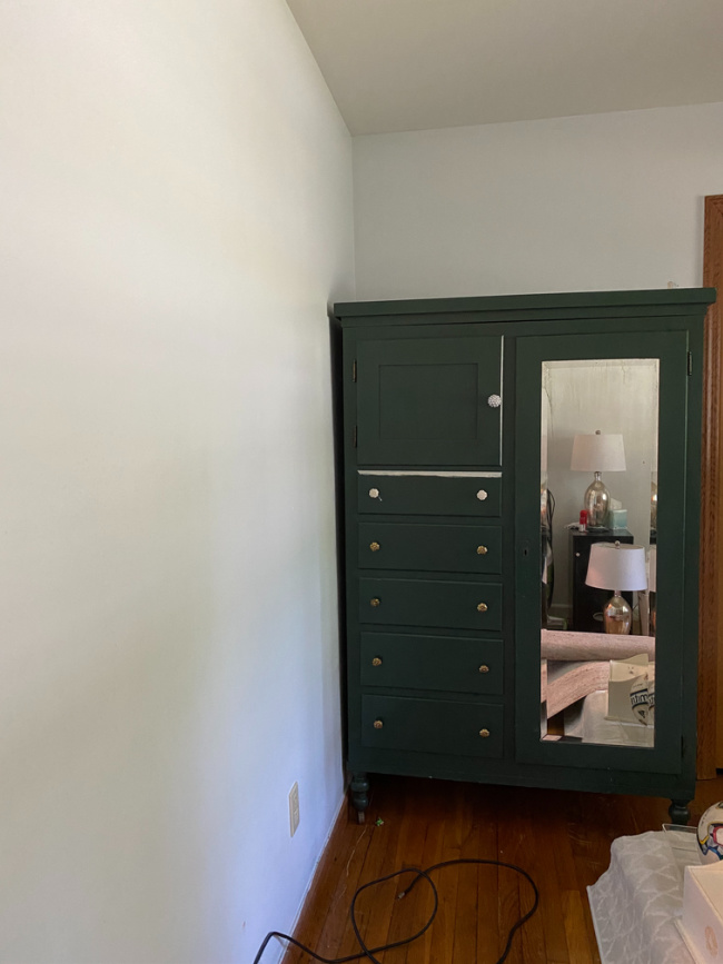 Green armoire in guest room before