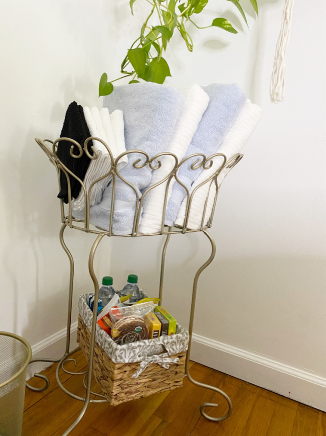 guest room snacks in basket and small gold trash can 