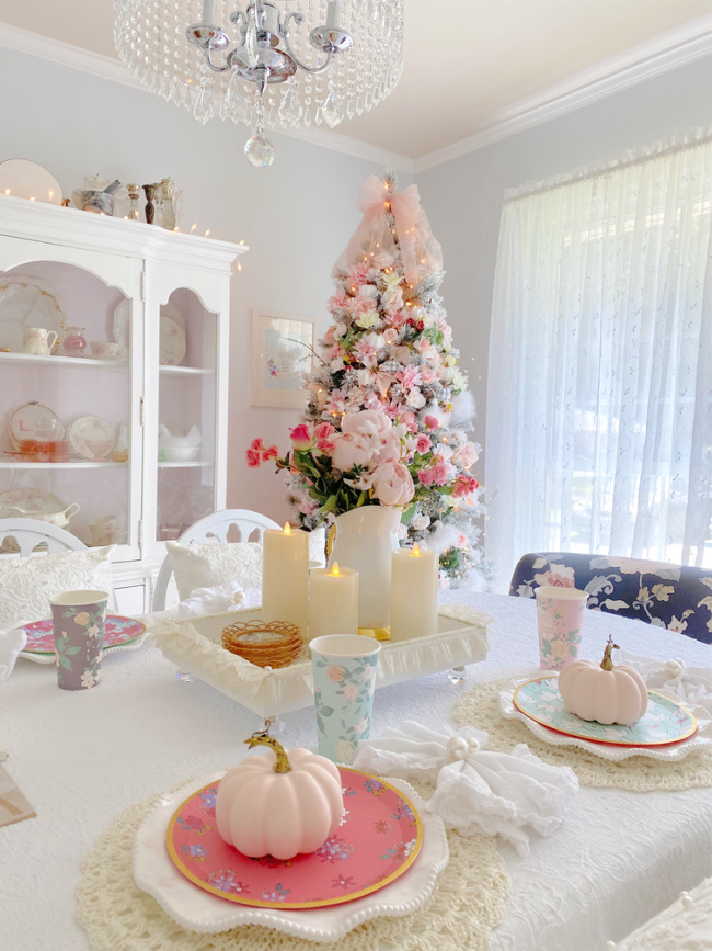 Fall dining room decor. pink pumpkins on table and fall tree in background