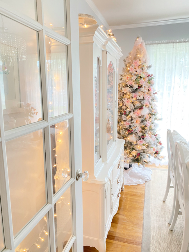 Feminine floral May Day Christmas tree with white china cabinet and french door in view