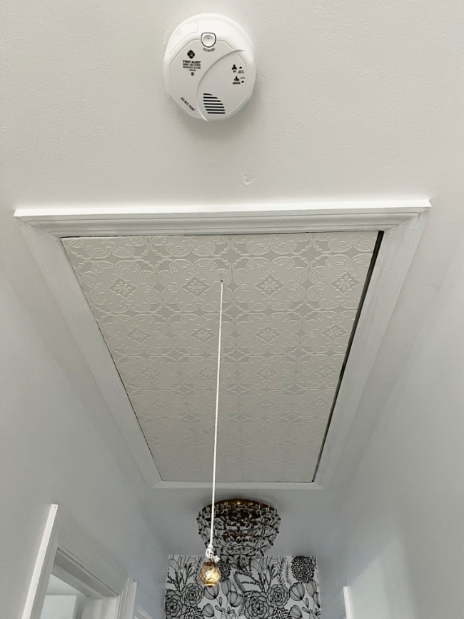 wallpapered attic access door in hallway