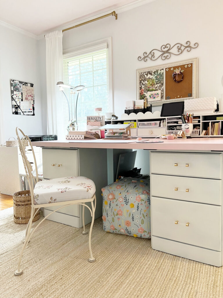 pink desk showing floral poof underneath and cream color rug