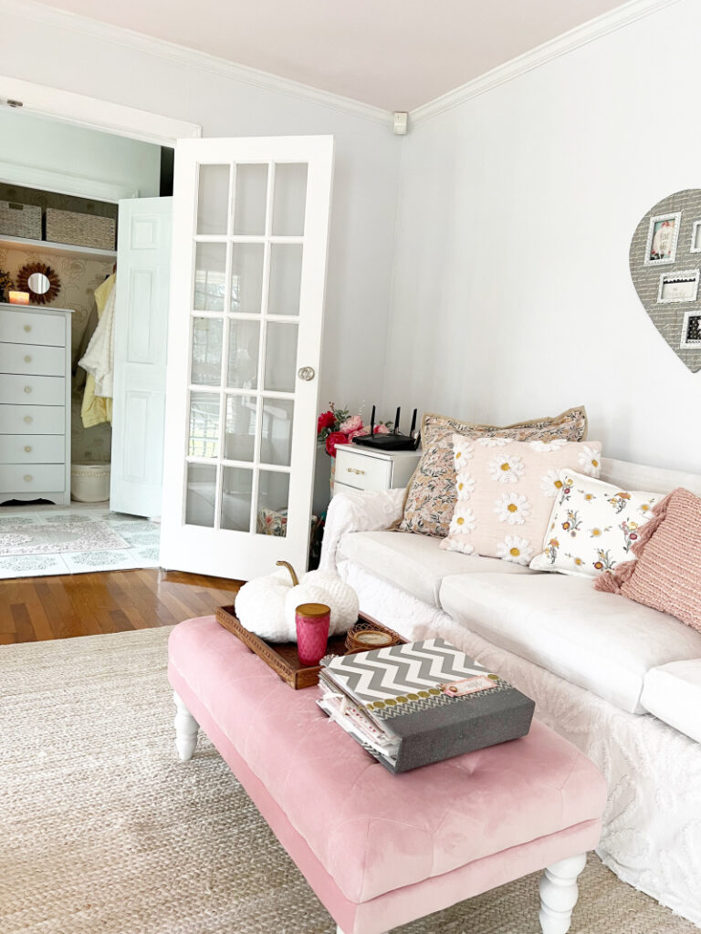 view of white velvet slip covered sofa, pink ottoman and view of from closet